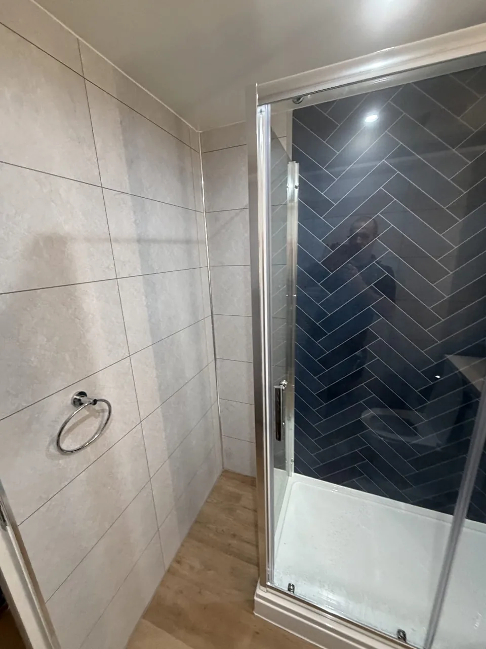 Glass shower enclosure with navy herringbone tiles