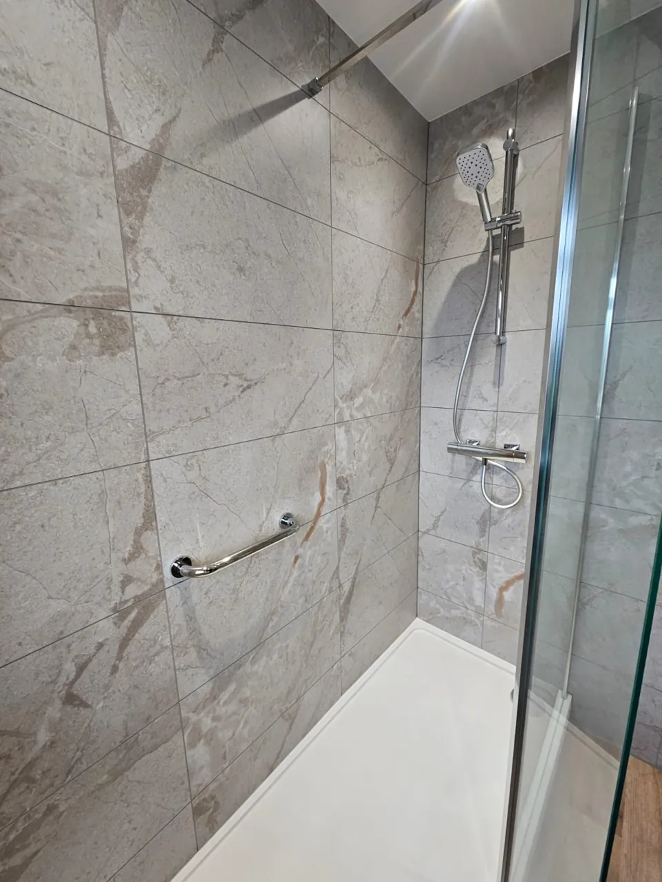 Walk-in shower with marble-effect walls and chrome fittings